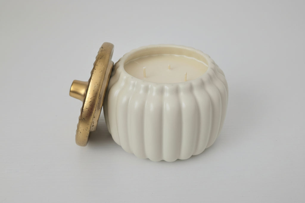 White ceramic container with a gold lid on a white surface