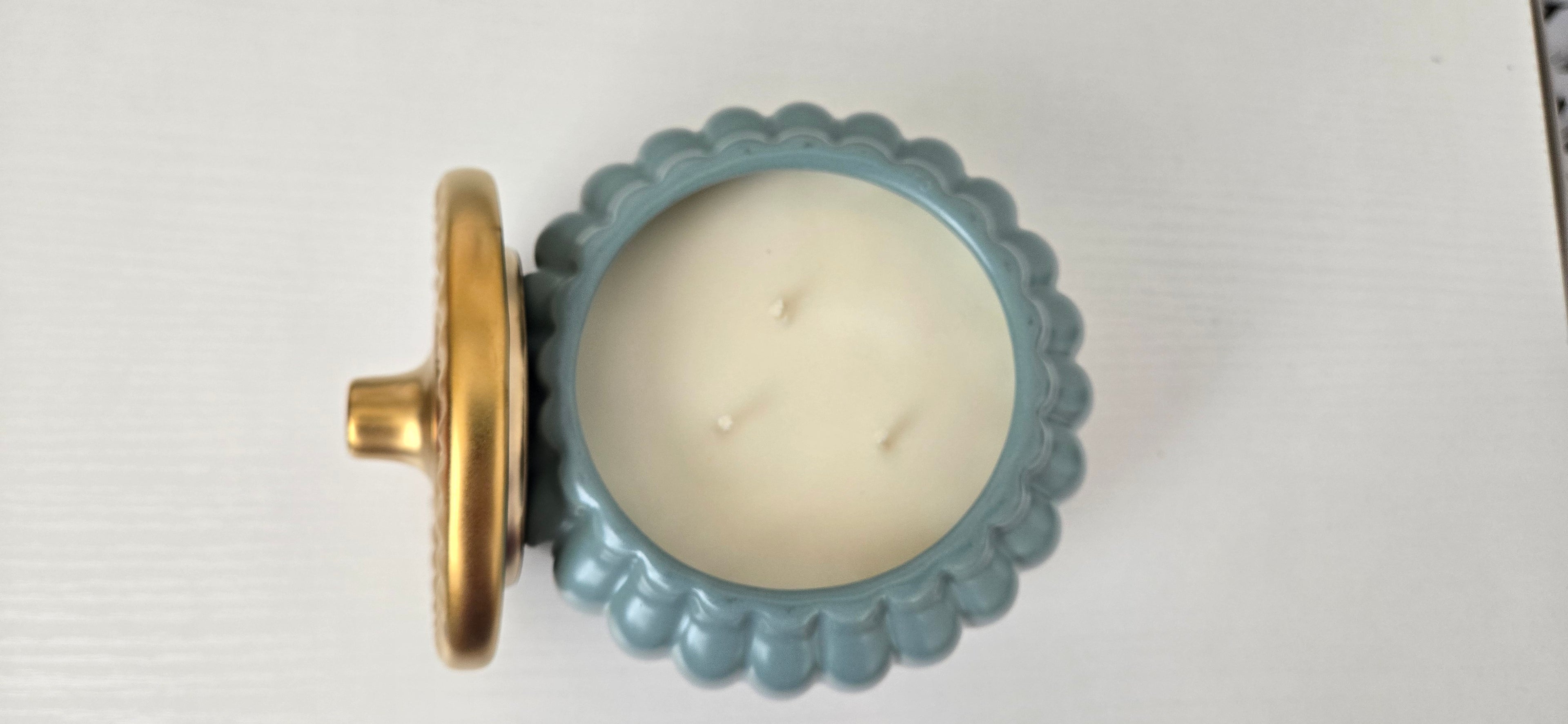 Candle in a decorative blue holder with a gold base on a white background