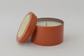 Candle in a terracotta container on a light gray background