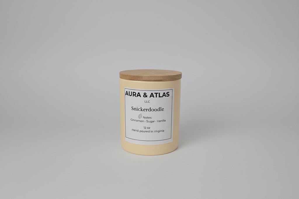 Candle with wooden lid labeled 'Aura & Atlas' on a white surface