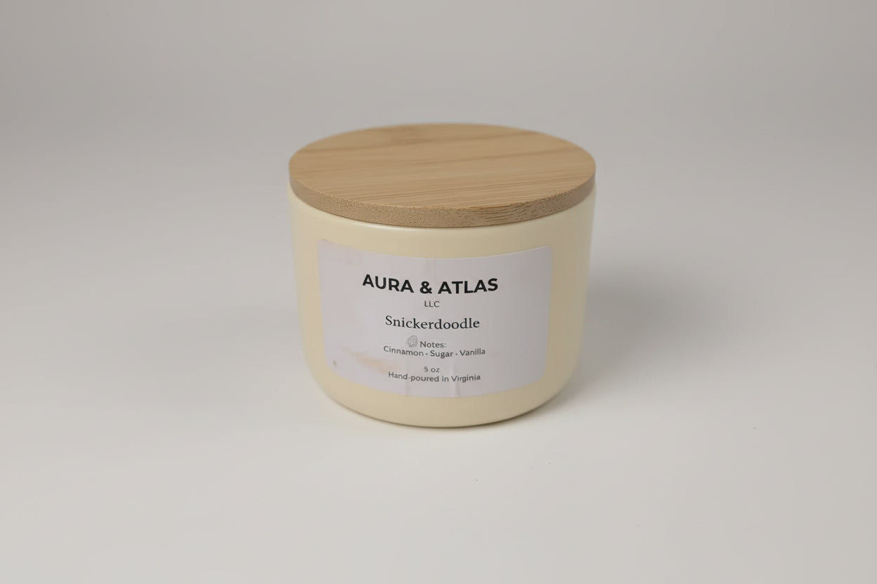 Candle jar with wooden lid labeled 'Aura & Atlas' on a white surface