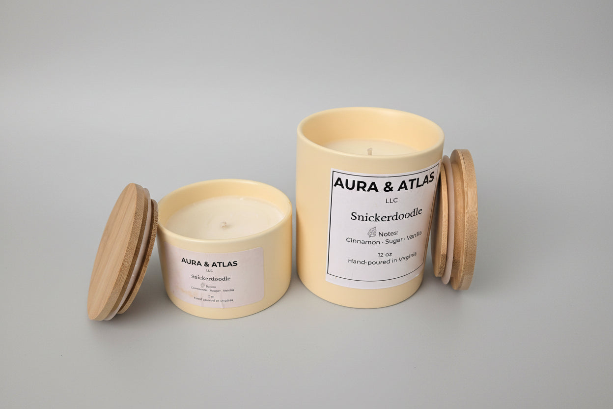 Two candles with wooden lids on a white surface, branded 'Aura & Atlas'.