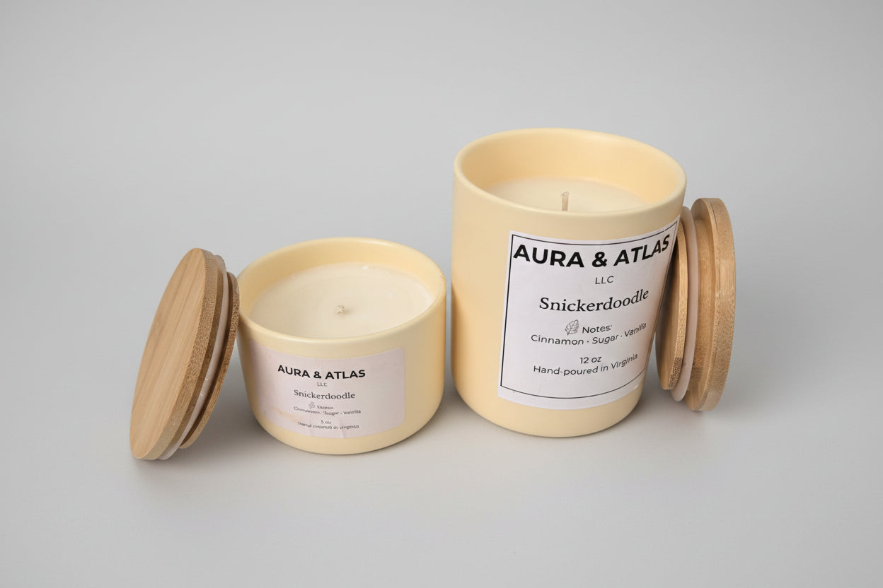 Two candles with wooden lids on a white surface, branded 'Aura & Atlas'.