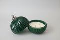 Green textured candle holder with a candle inside on a white surface