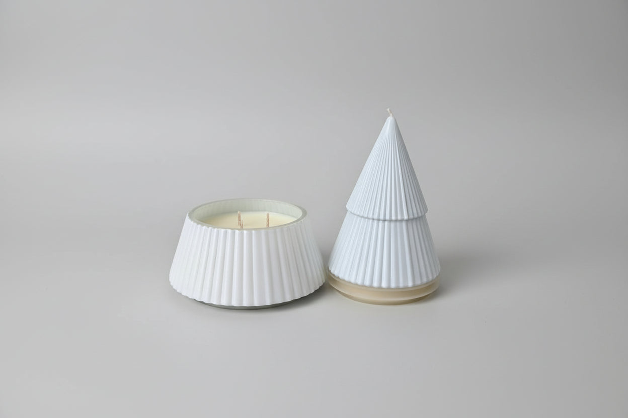 Two white textured containers on a light surface, one with a lit candle inside.