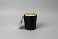 Black candle with a gold interior on a white surface