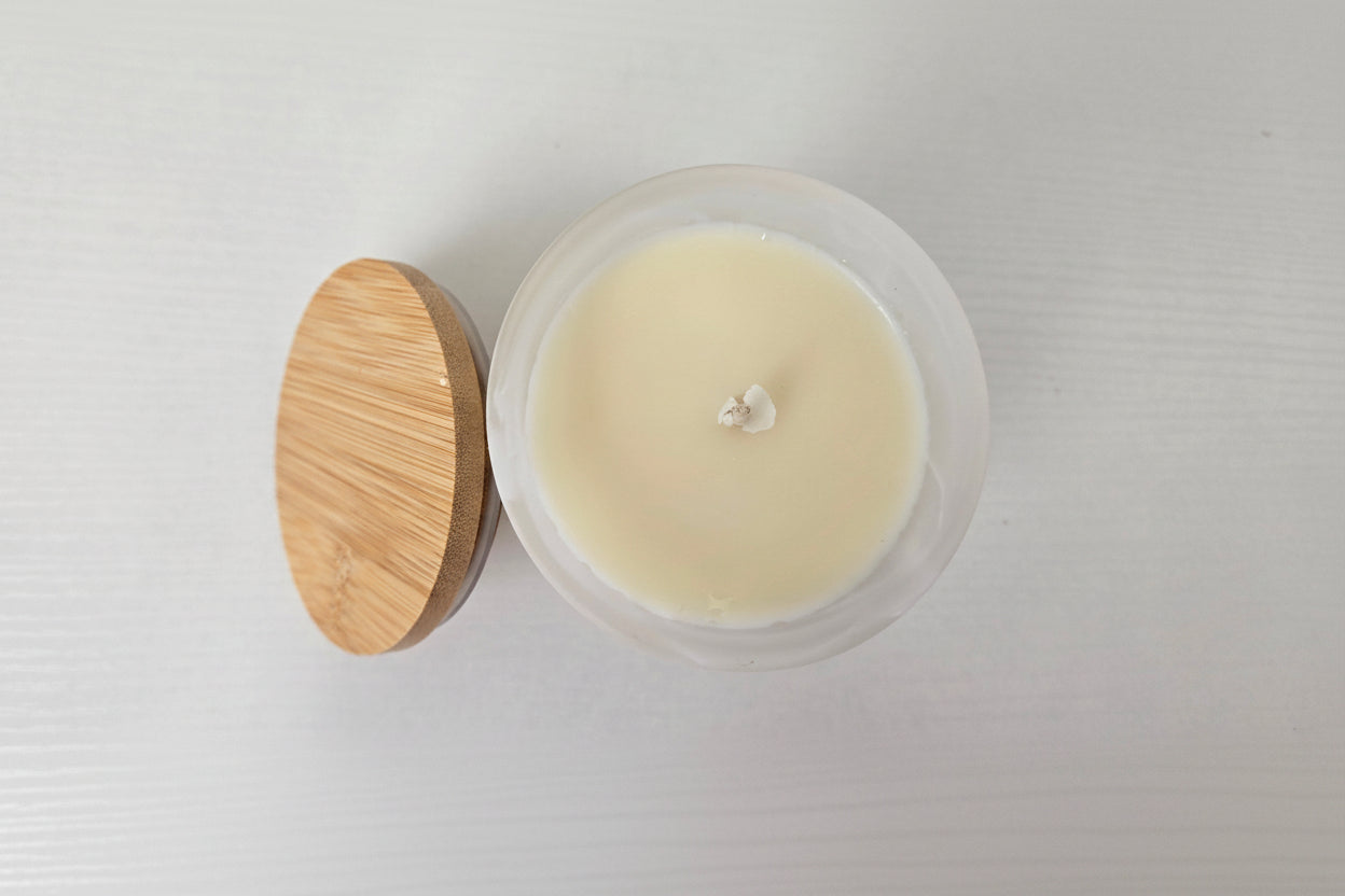 Candle in a glass jar with a wooden lid on a white background