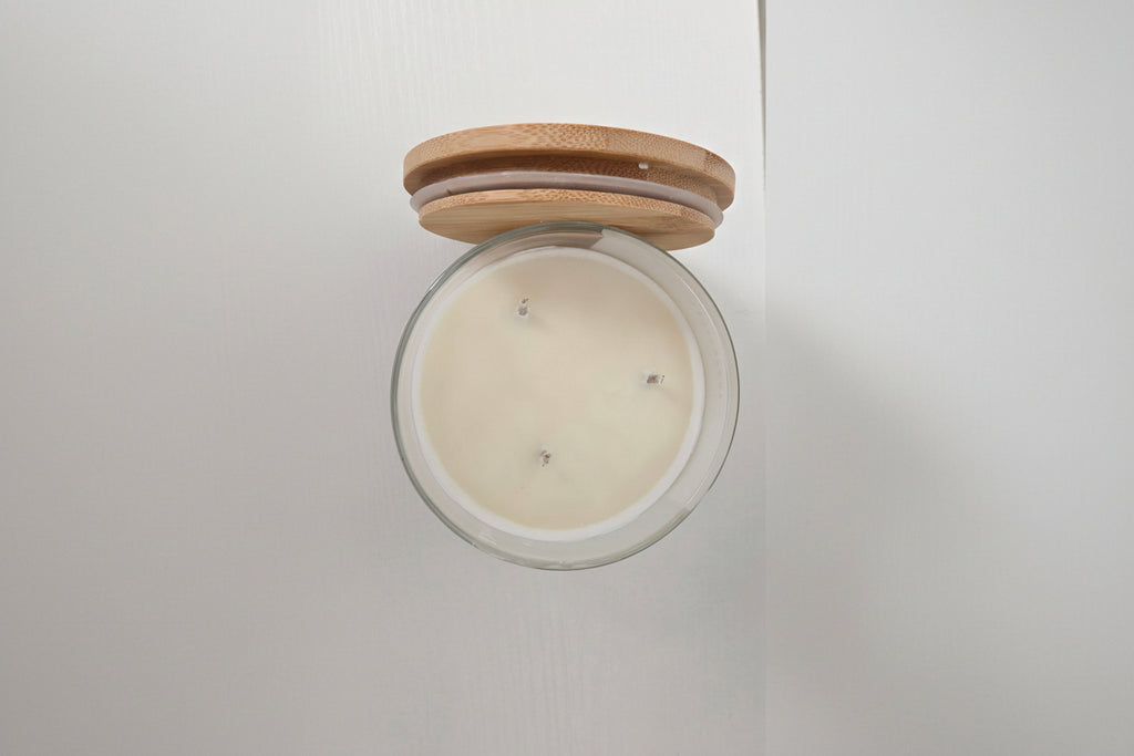 Candle in a glass jar with a wooden lid on a white background