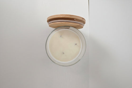 Candle in a glass jar with a wooden lid on a white background