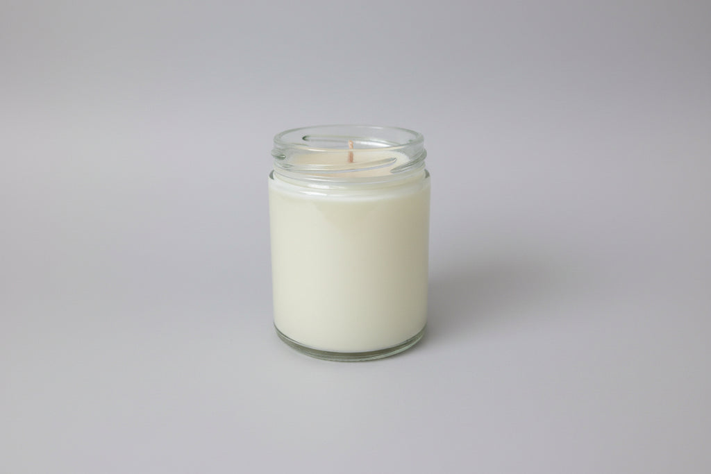 Candle in a glass jar on a white surface