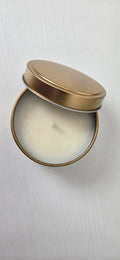 Candle in a round tin with a gold lid on a white background