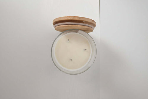 Candle in a glass jar with a wooden lid on a white background