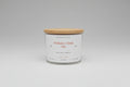 White candle with wooden lid on a white surface
