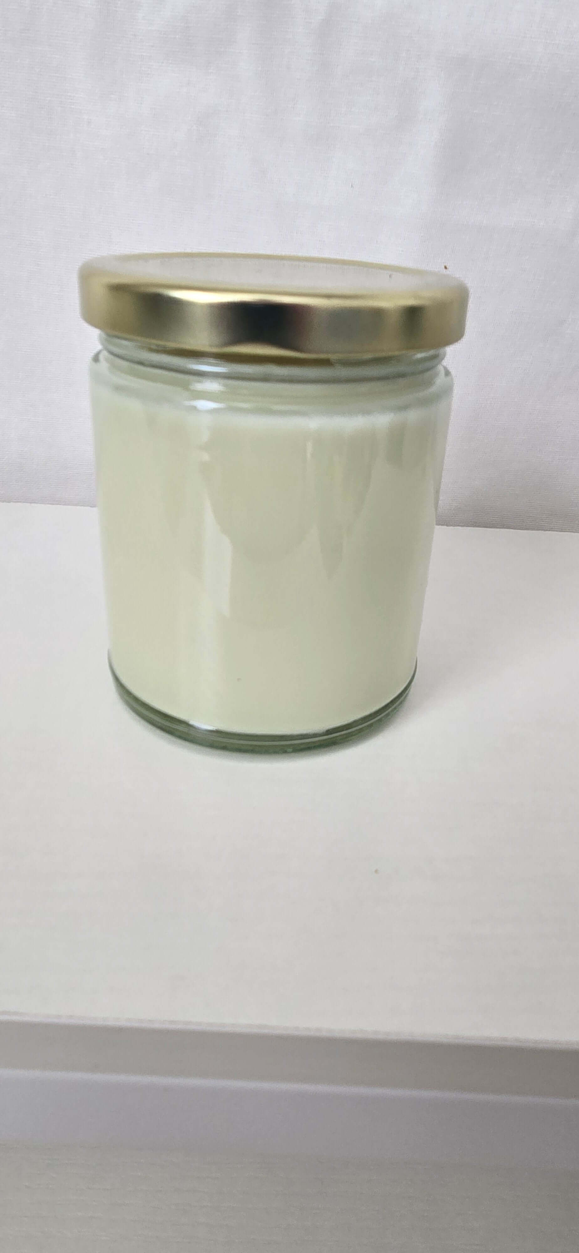 Clear glass jar with a gold lid on a white background