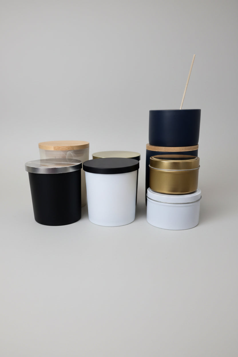 Set of cylindrical containers with black, gold, and white lids on a white surface.